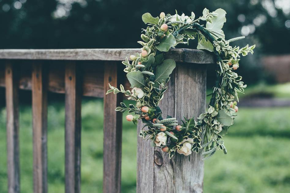 Two women crafting a rustic fall wreath with eucalyptus and dried oranges at a wooden table